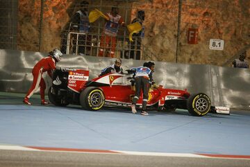 Маршалы и Себастьян Феттель толкают машину Ferrari в безопасную зону