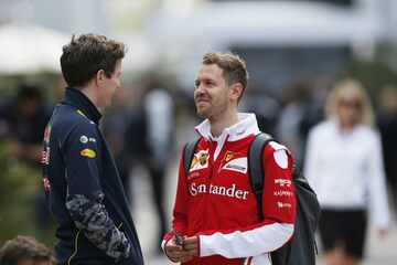Гонщик Ferrari Себастьян Феттель общается в паддоке с работником команды Red Bull