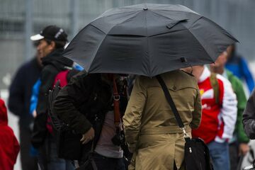 Болельщики прячутся от дождя под зонтом